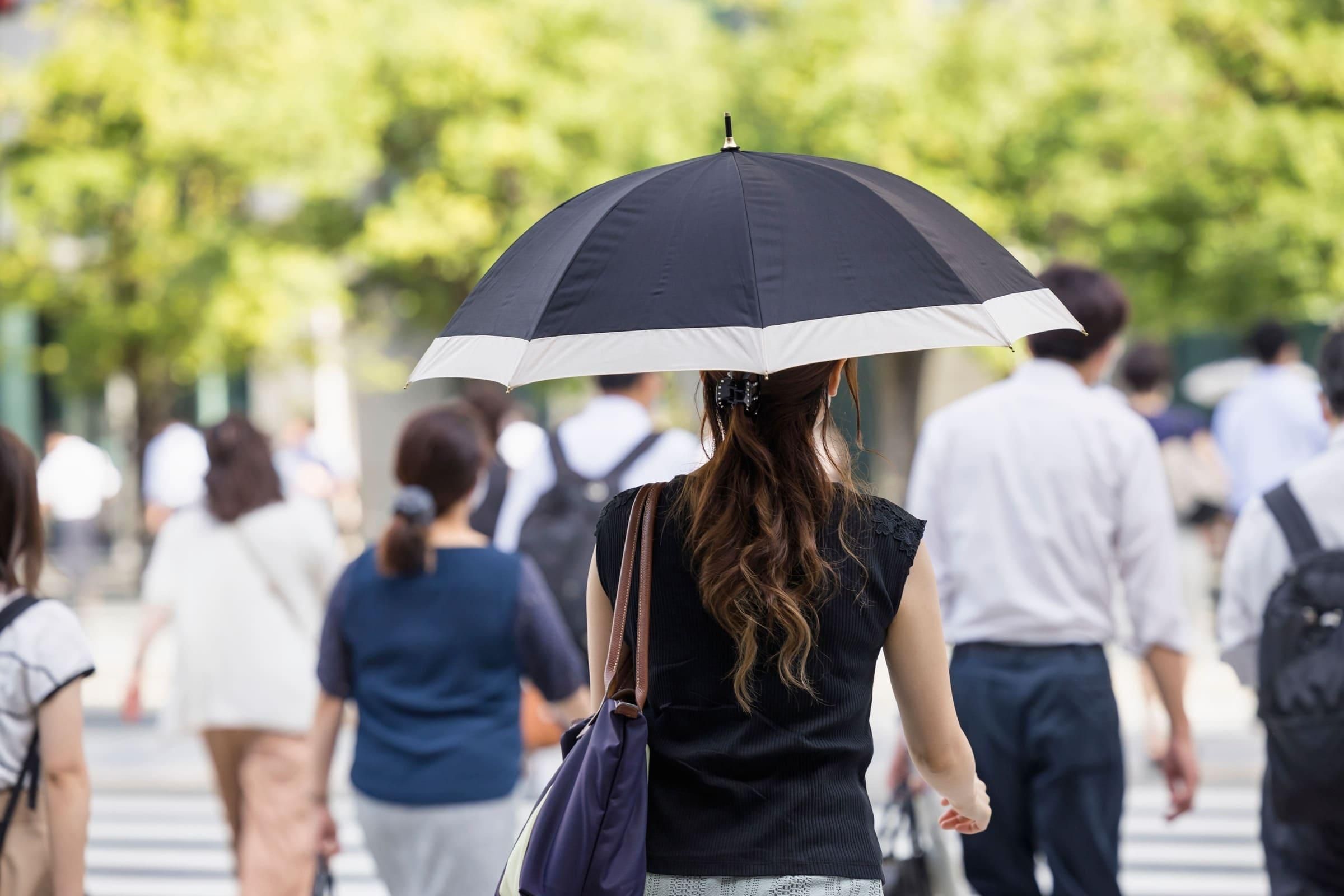汗対策で日傘をさしている女性